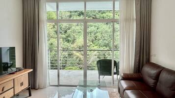 A living room with a glass coffee table, leather sofa, and a TV on a wooden cabinet.