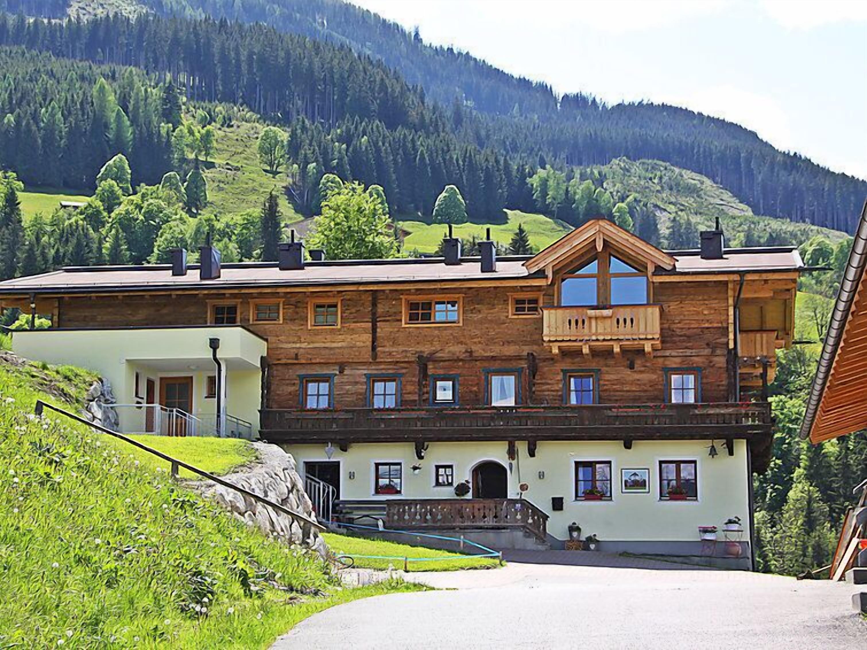A two-story wooden building with a balcony, a stone staircase, and a view of a mountainous landscape.