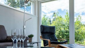 A modern living room with a glass table, a leather chair, and a sofa. There are three wine glasses on the table. - Saarland by Interhome (Dittishausen)