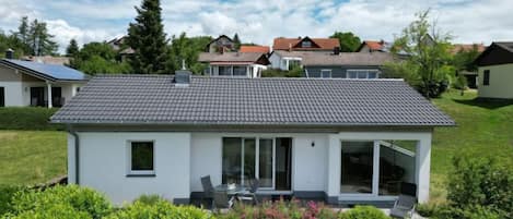 Et moderne hus med to etager, gråt tegltag, store vinduer og en velholdt have.