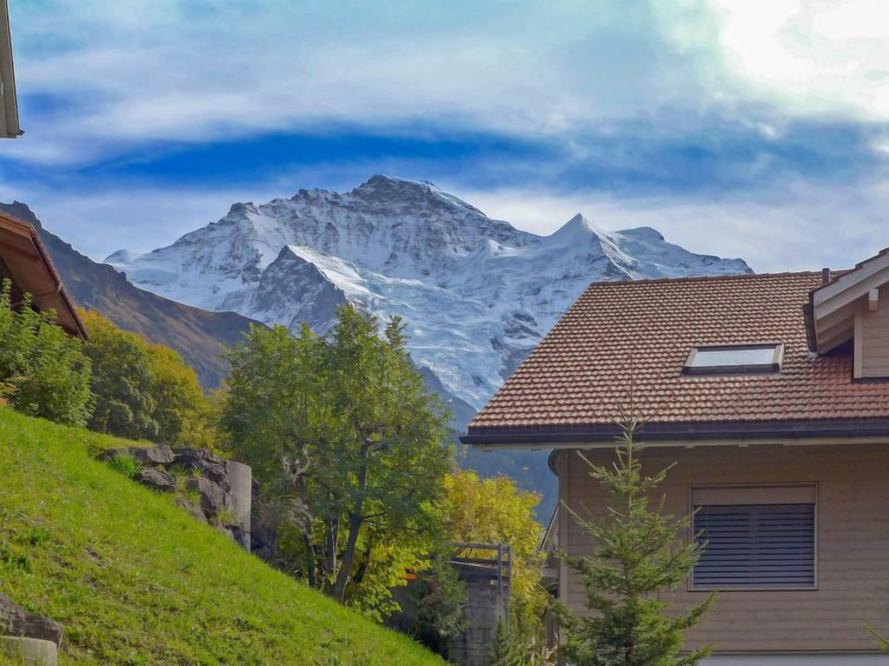Una casa amb teulada inclinada, una finestra petita i vista a una muntanya nevada.