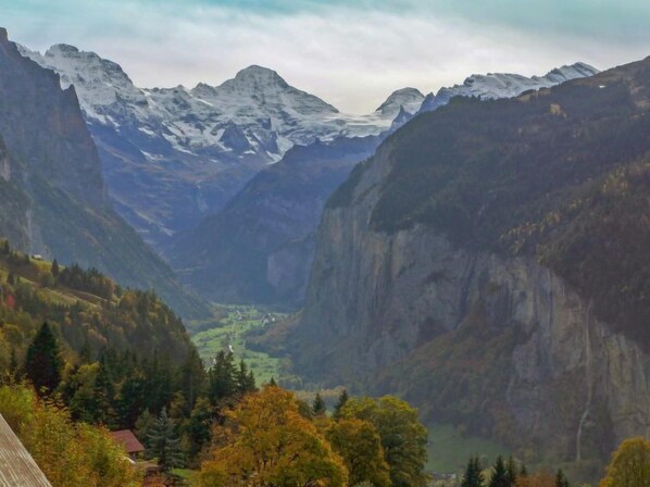 A valley with mountains, a river, and a small house.