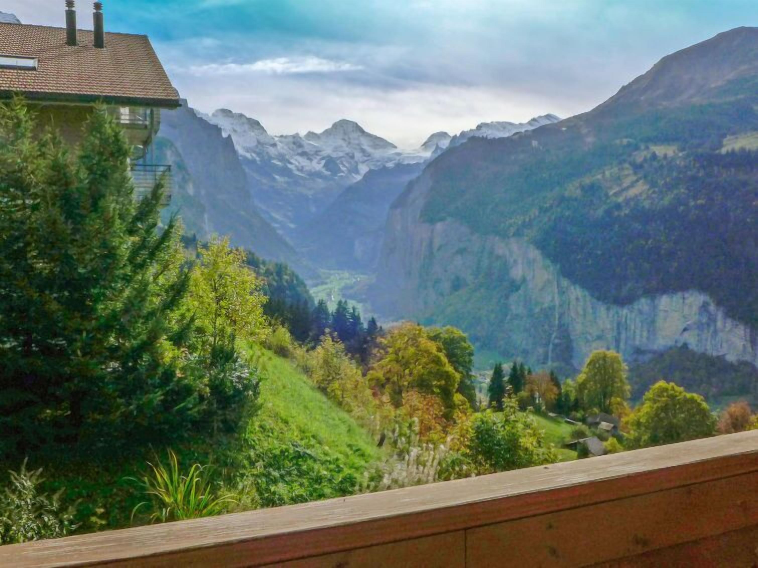 Paisagem montanhosa com uma casa em primeiro plano e um vale ao fundo.