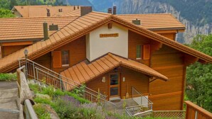 A wooden chalet with a sloped roof, a staircase leading to the entrance, and a sign reading "PRIMAVERA." - Panorama Apt. P by Interhome (Wengen)