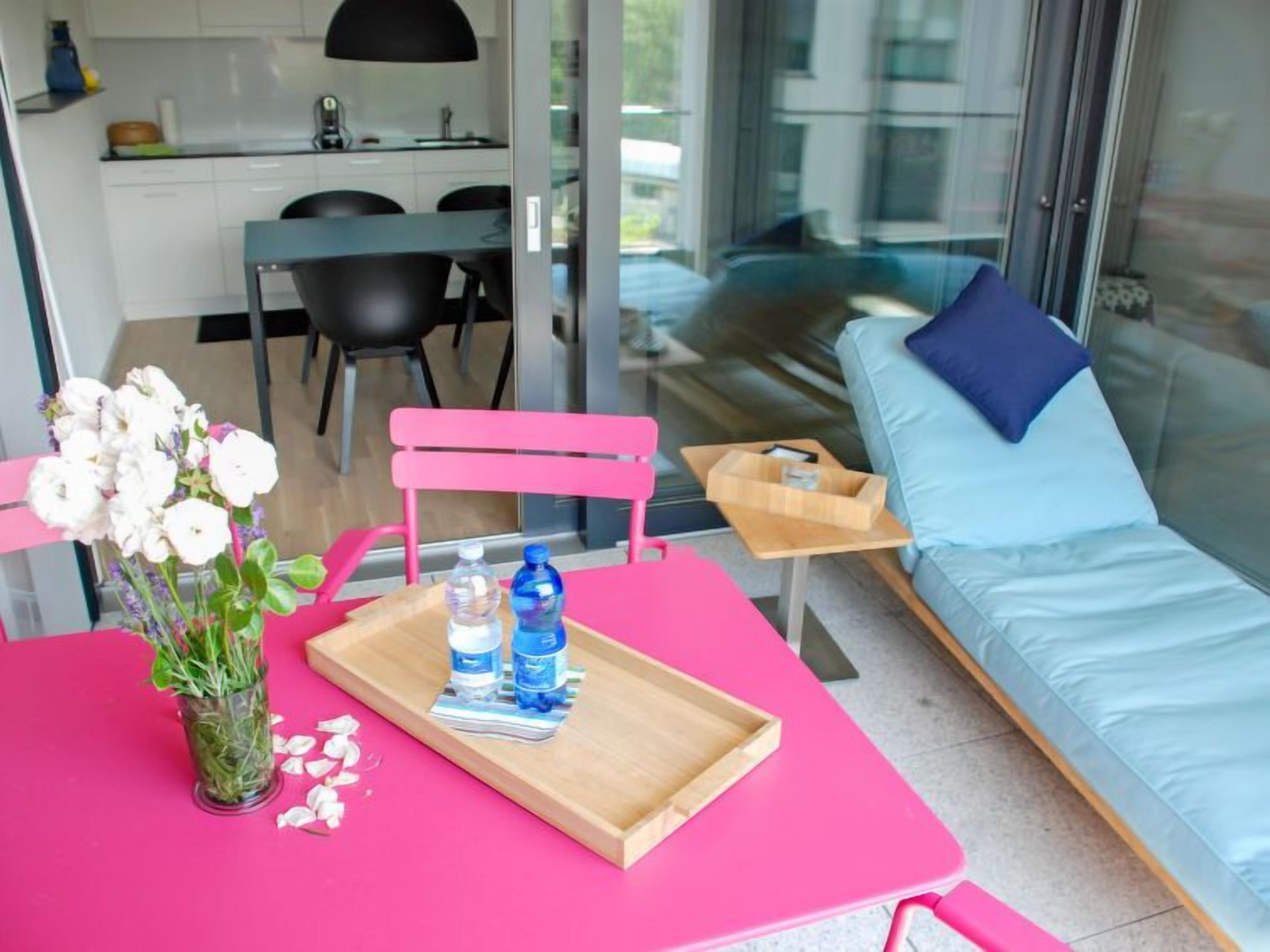 A modern living space with a pink table, a blue sofa, and a glass wall.