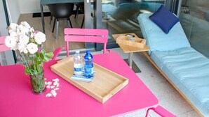 Un espacio habitable moderno con una mesa rosa, un sofá azul y una pared de vidrio.