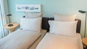 Una habitación de hotel con dos camas, un cuadro colgado en la pared y dos lámparas de pie.