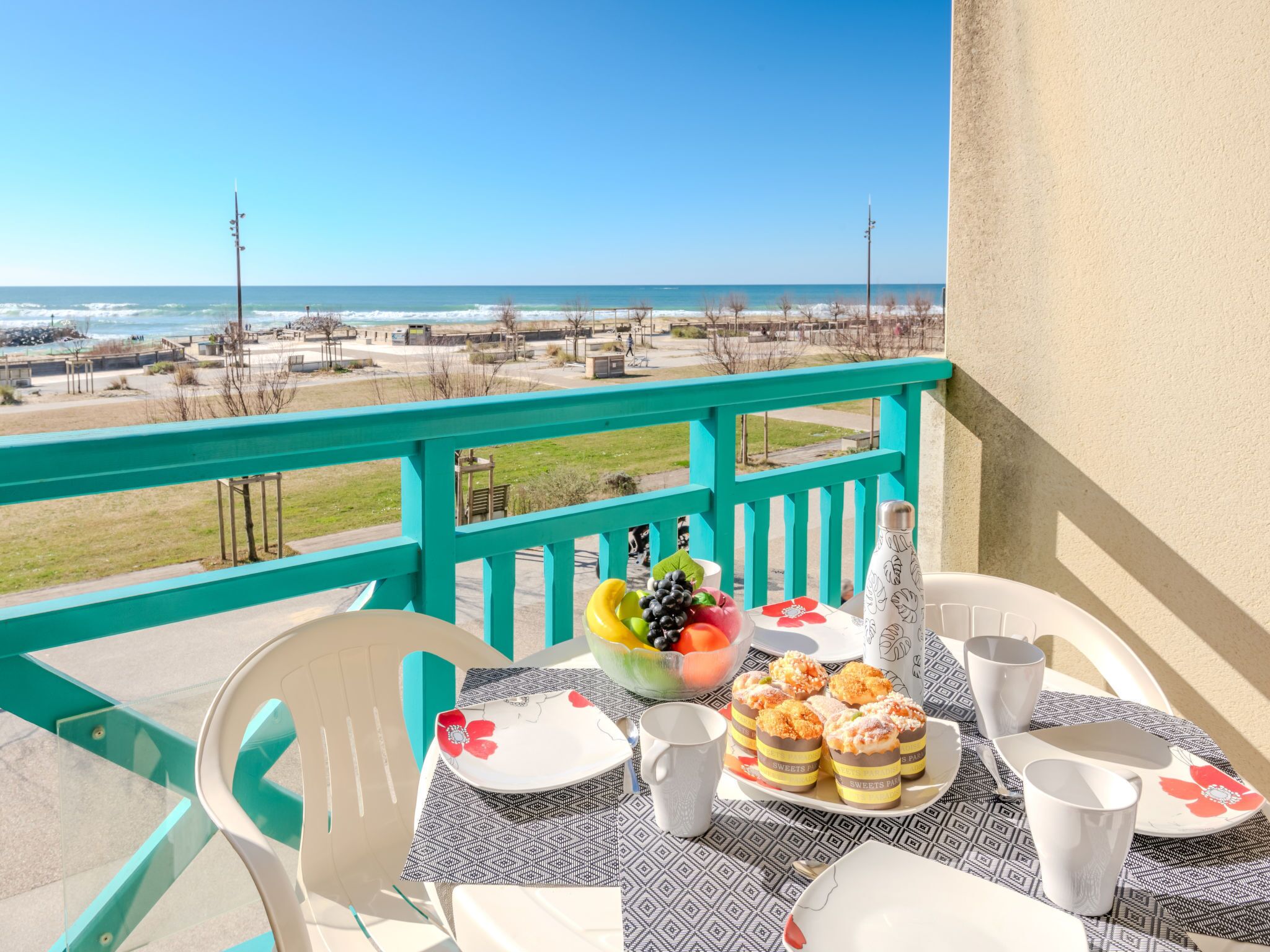 Un balcone con un tavolo apparecchiato per due, vista sulla spiaggia e sull'oceano.