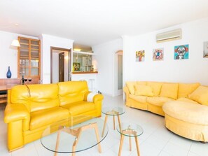 A living room with two yellow sofas, a glass coffee table, and a kitchen in the background. - Port Rhodes by Interhome (Empuriabrava)