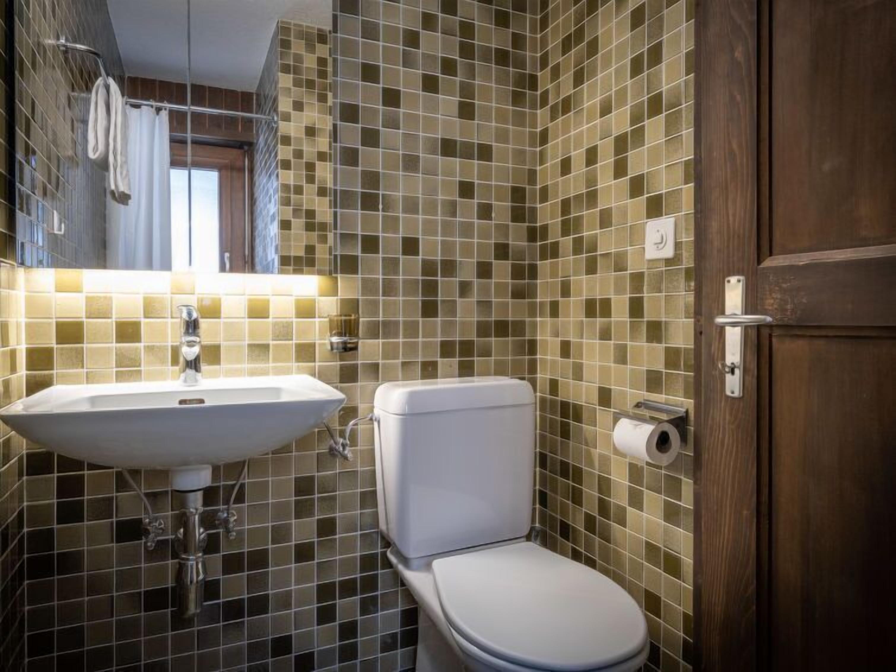A bathroom with a sink, toilet, and a mirror.