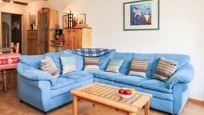Un soggiorno con un divano blu, un tavolino di legno con della frutta e un mobiletto in legno.