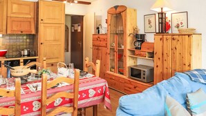 Una cucina accogliente con mobili in legno, un tavolo da pranzo per quattro persone e un divano blu nella zona soggiorno.