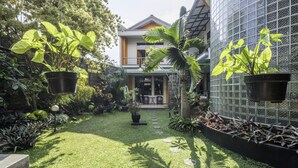 A well-maintained garden with a pathway leading to a house with a balcony. - Collection O Kebon Jeruk Near Taman Balai Kota (Bandung)