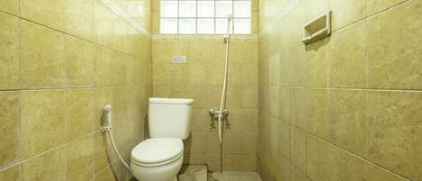 A small, tiled bathroom with a toilet, a shower, and a window.