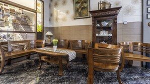 A dining area with wooden furniture, a marble floor, a wall with a framed picture, and a window with various items displayed. - Collection O Kebon Jeruk Near Taman Balai Kota (Bandung)