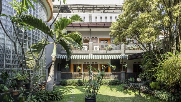 A courtyard with a potted plant, a small garden, and a building with a balcony. - Collection O Kebon Jeruk Near Taman Balai Kota (Bandung)