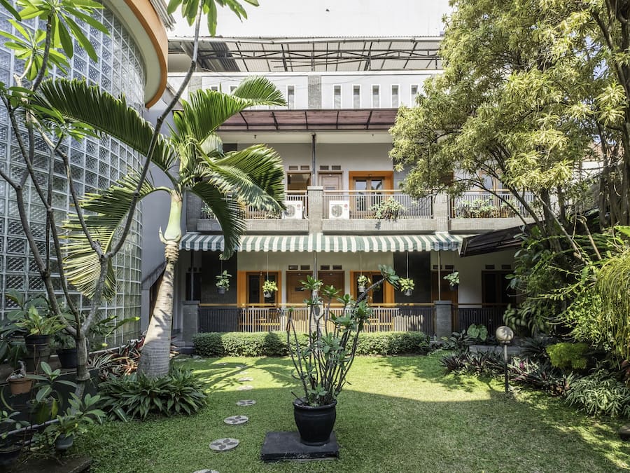 Um pátio com planta em vaso, um pequeno jardim e um edifício com varanda.