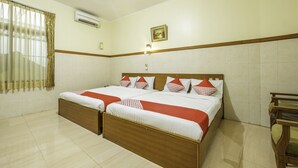 A double bed with a wooden headboard, a bedside table, and a window with curtains. - Collection O Kebon Jeruk Near Taman Balai Kota (Bandung)