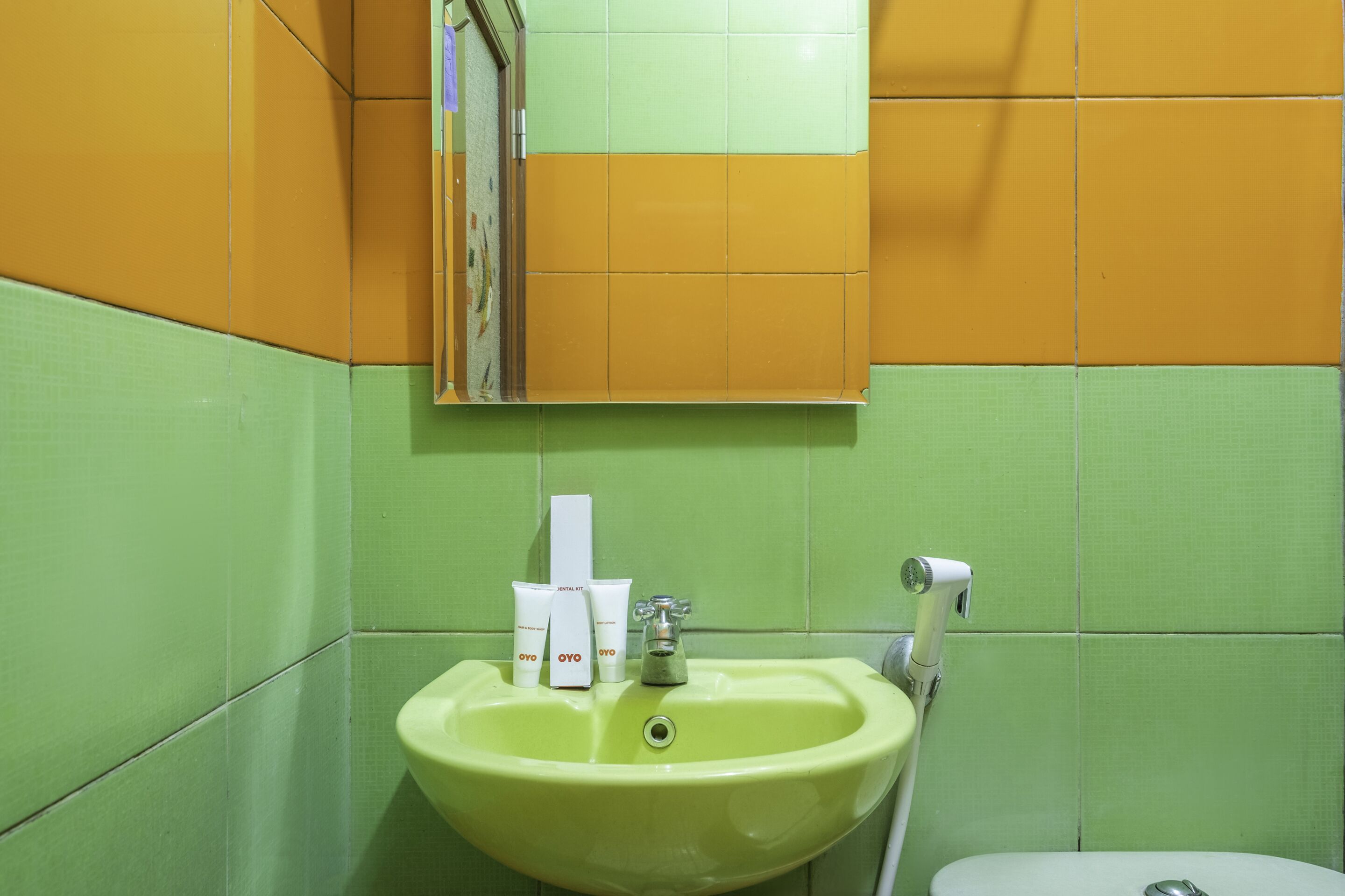 Casa de banho com lavatório verde, espelho e artigos de higiene pessoal.
