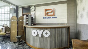 A reception desk with a clock and a sign for 'Patricia Hotel' and 'OYO'. - Collection O Kebon Jeruk Near Taman Balai Kota (Bandung)