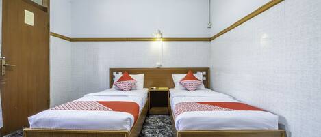 A hotel room with two beds, a wooden headboard, a nightstand, and a wall-mounted air conditioner.