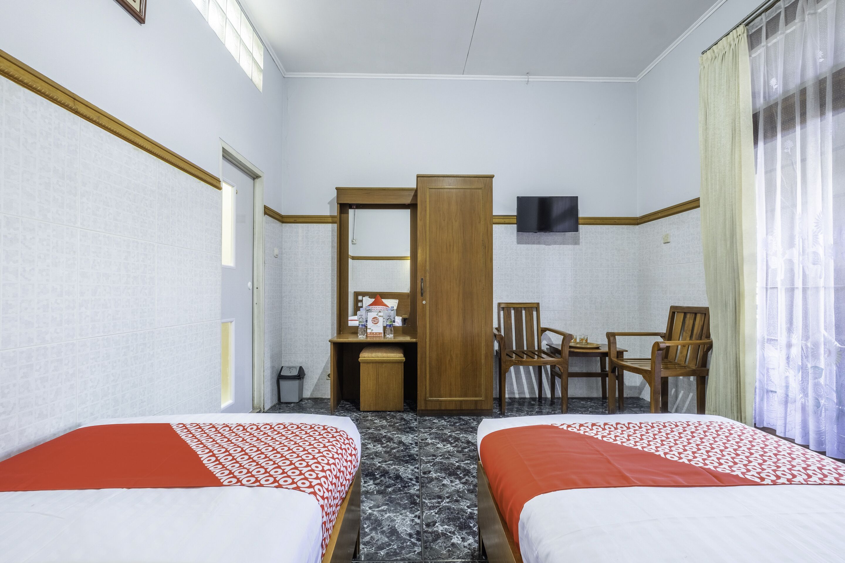 Habitación de hotel con dos camas, un escritorio, una silla y un televisor.
