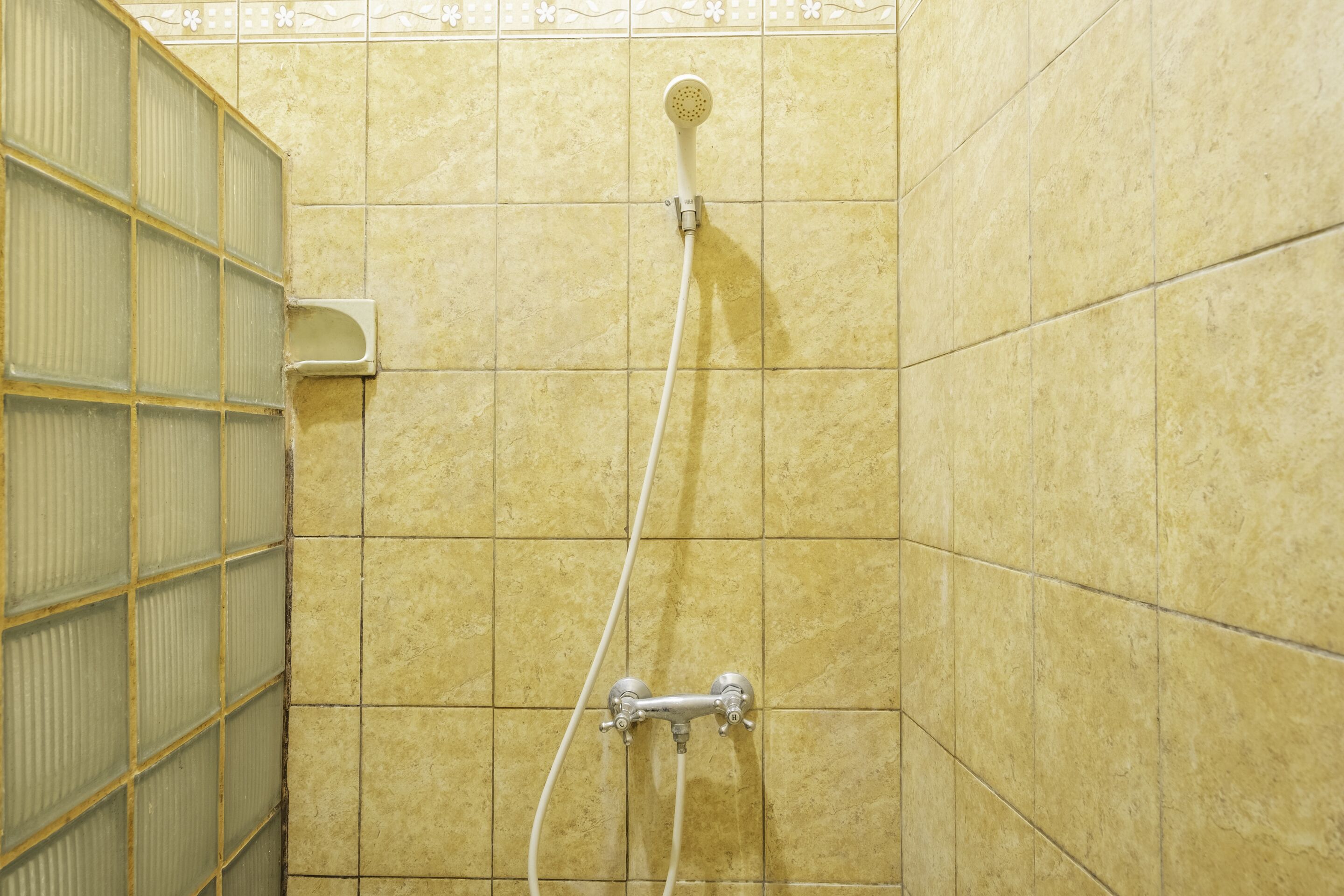 A shower area with tiled walls, a glass door, and a showerhead.