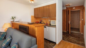 Een kleine keuken met houten kastjes, een magnetron en een kleine koelkast.