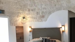 Een slaapkamer met een stenen plafond, een bed met een beige sprei en twee bedlampen.