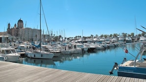 A marina with numerous boats docked, a wooden pier, and a historic building with domed architecture in the background. - Boulouris Mimosa by Interhome (Saint-Raphaël)