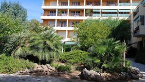 A multi-story hotel with balconies, surrounded by tropical vegetation and a rocky landscape. - Boulouris Mimosa by Interhome (Saint-Raphaël)