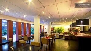 A spacious dining area with high ceilings and large windows, featuring multiple tables and chairs. - Royal Residence Iffco Chowk (Gurugram)