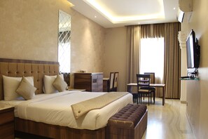A hotel room with a large bed, a desk, and a television. - Royal Residence Iffco Chowk (Gurugram)