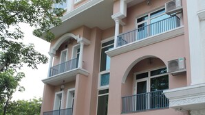 A multi-story building with balconies, a covered outdoor seating area, and potted plants. - Royal Residence Iffco Chowk (Gurugram)