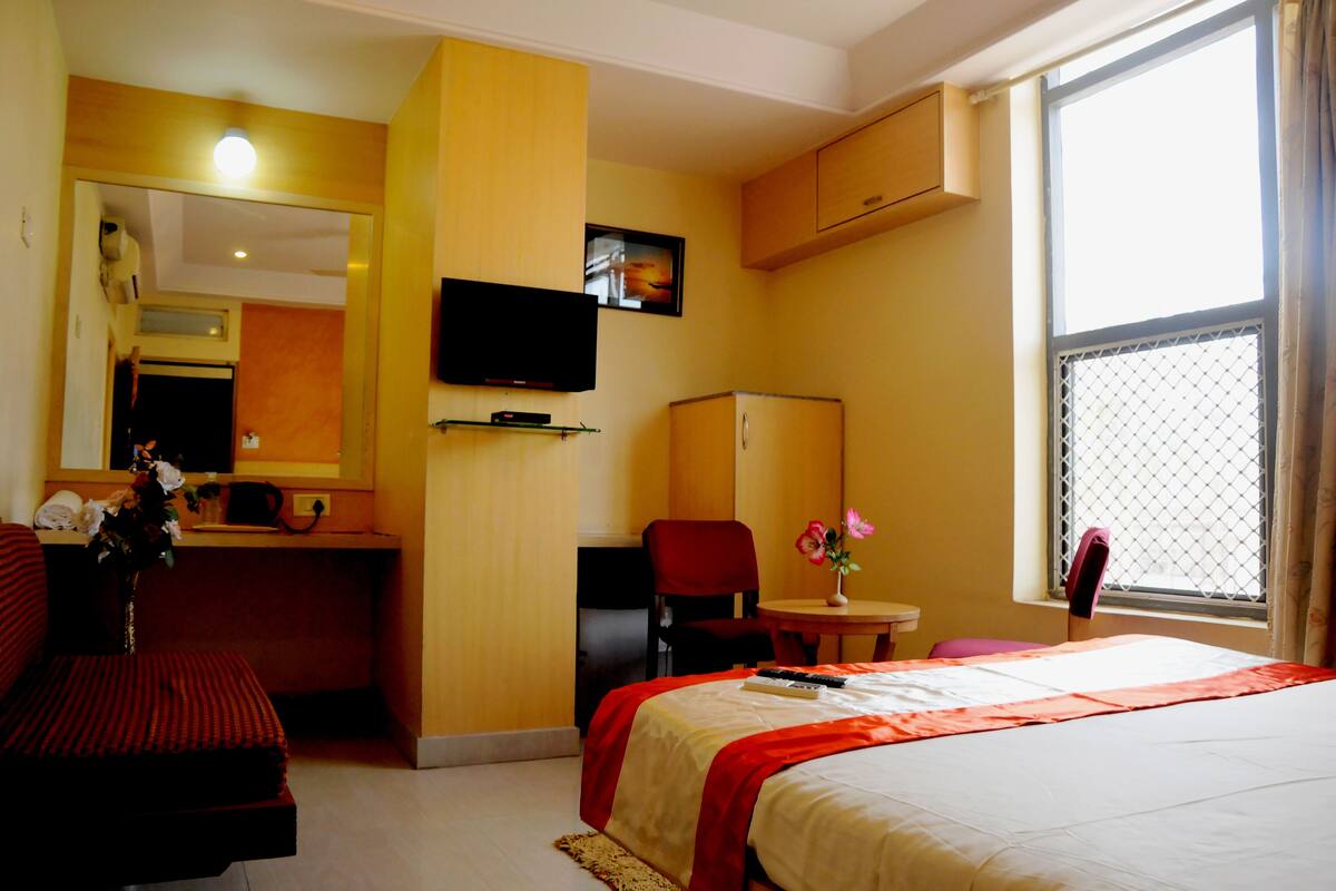 Habitación de hotel con cama, escritorio, silla, televisión y ventana con vistas.
