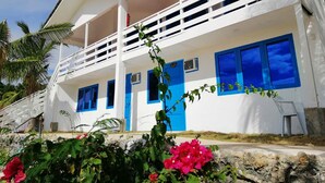 A white building with blue accents, including doors and windows, and a balcony.