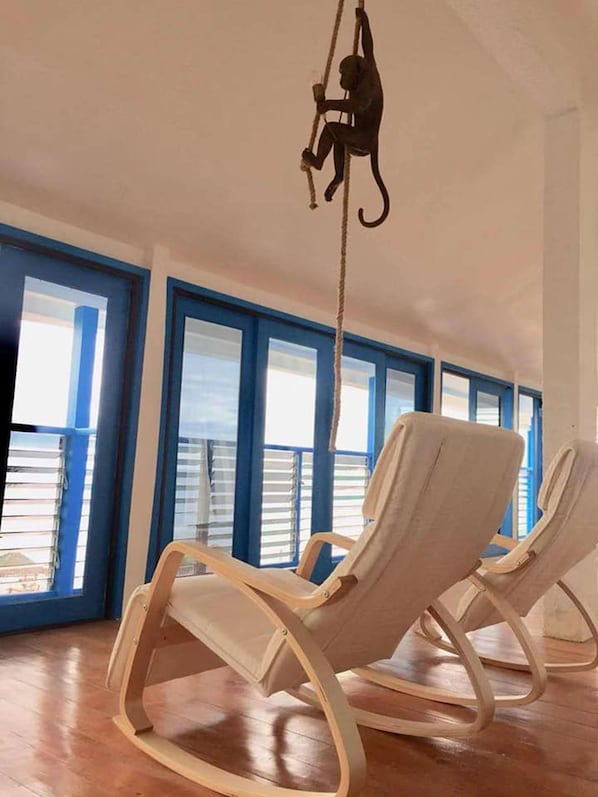 A room with two rocking chairs, a rope hanging from the ceiling, and large windows with blue frames. - Eastern Garama Resort (San Juan)