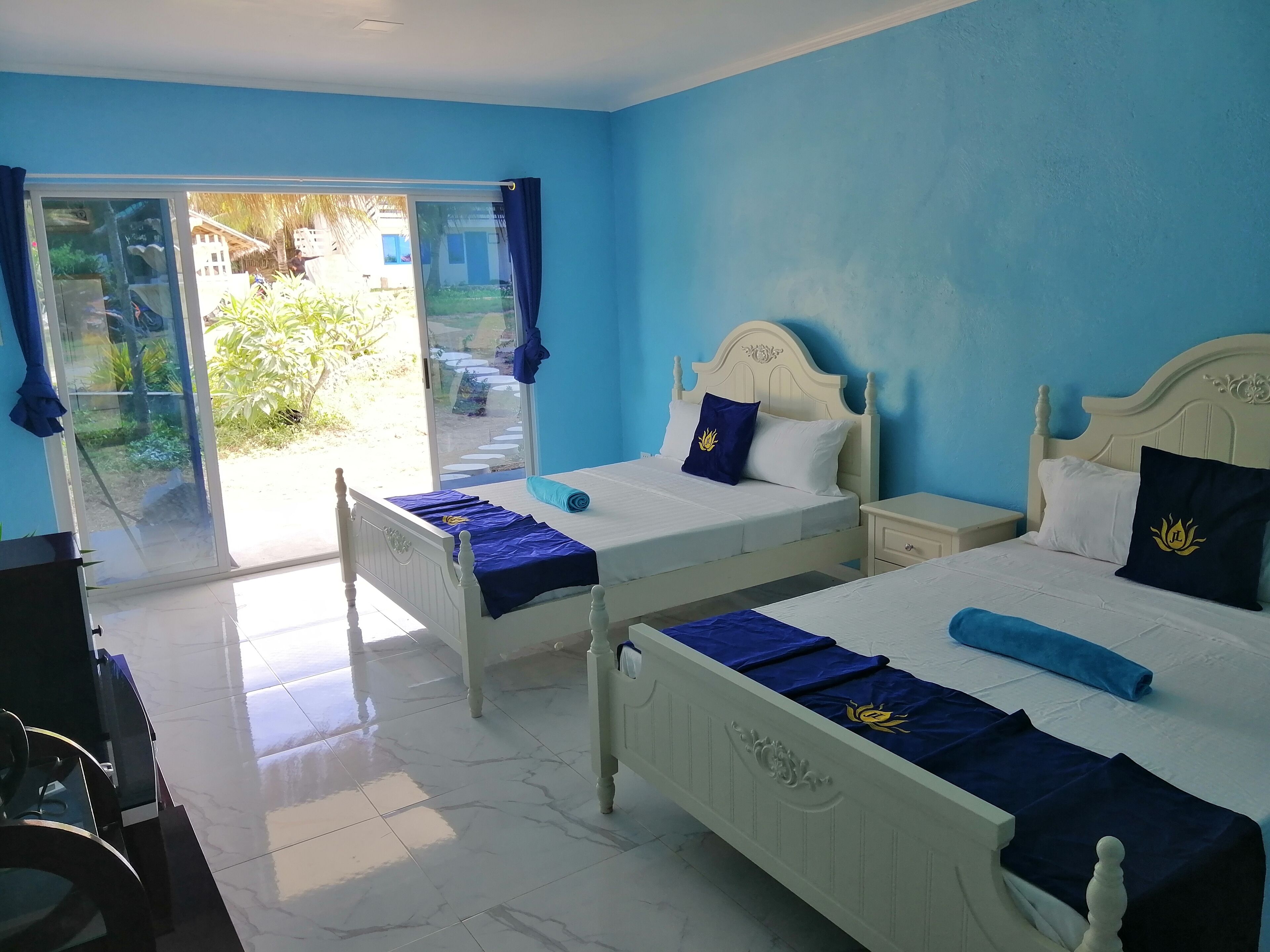 A hotel room with two beds, a desk, and a view of the outside.