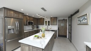A modern kitchen with stainless steel appliances, a marble countertop, and wooden cabinets.