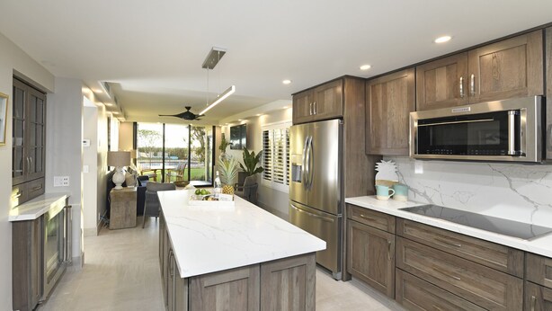 A modern kitchen with wooden cabinets, stainless steel appliances, and a marble countertop.