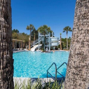 A swimming pool with a water slide, surrounded by palm trees and a clear sky. - Huge at 2,360 SqFt, Golf Cart & 4 Bikes! 4 WaterColor Pools, Beach Club & Camp - Bess Place on Earth (Santa Rosa Beach)