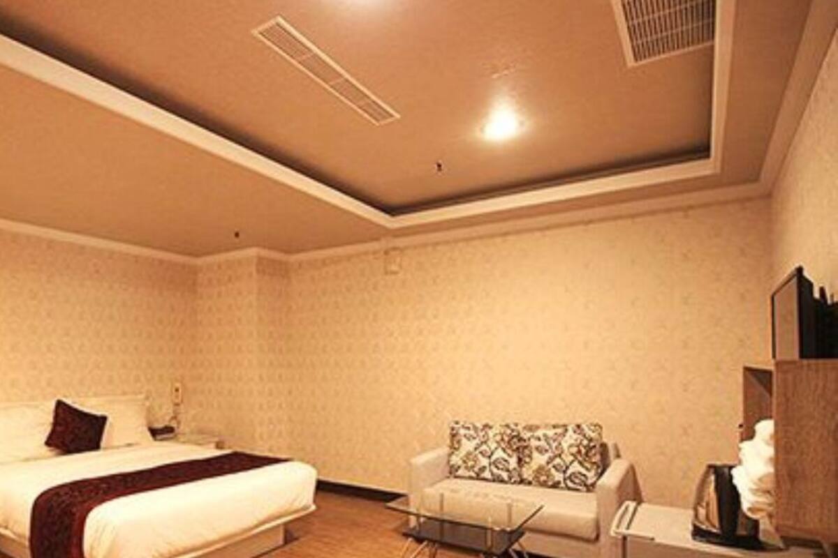 A bedroom with a bed, a nightstand, a chair, and a dresser.