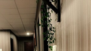 A hallway with a wooden floor, a white reception desk, and a wall-mounted plant. - Ya Tai Hotel (Kaohsiung)