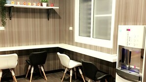 A modern kitchen with a white countertop, two black and two white chairs, a built-in window, and a water dispenser. - Ya Tai Hotel (Kaohsiung)