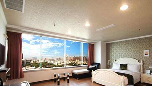 A hotel room with a large window, a bed, a bedside table, and a chair. - Ya Tai Hotel (Kaohsiung)