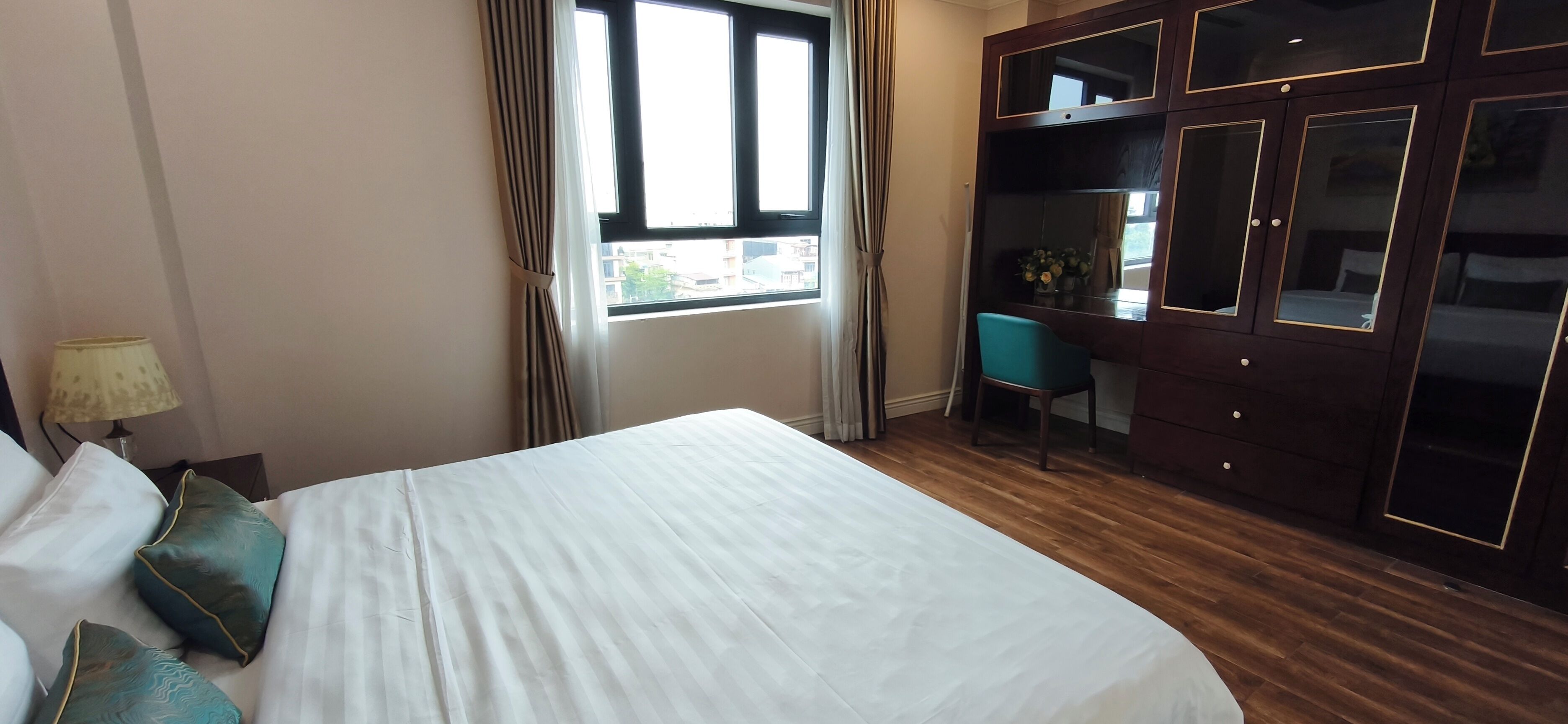 A hotel room with a bed, a desk, and a wardrobe.
