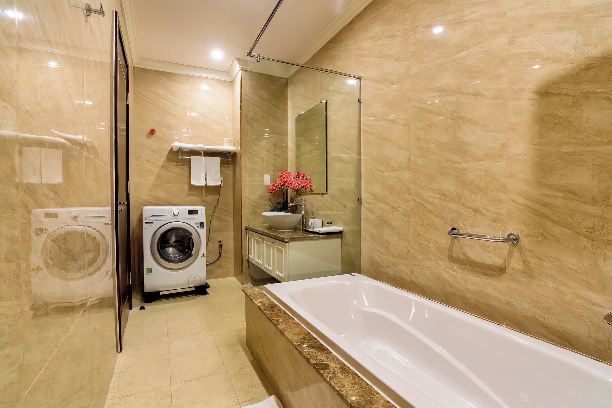 Une salle de bain moderne dotée d’une douche à parois de verre, d’un lave-linge encastré, d’une baignoire et d’un meuble-lavabo avec un miroir.