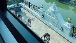 Vista desde un balcón sobre un río, con un puente y edificios al fondo.