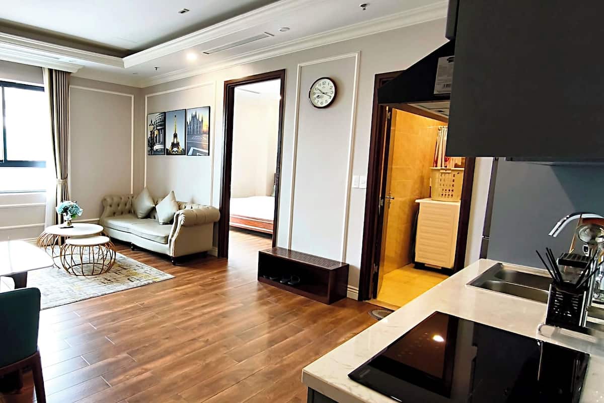 Un salon moderne comprenant un canapé, une table à manger et des chaises, un coin cuisine avec un évier et une cuisinière, et une grande fenêtre avec des rideaux.