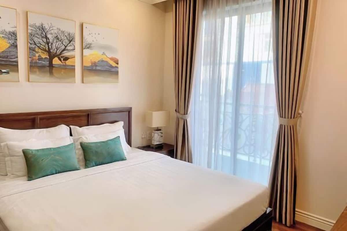 Une chambre d’hôtel avec un grand lit, une tête de lit en bois et trois tableaux accrochés au mur.